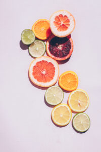 Various slices of citrus fruits laying on a light pink background.